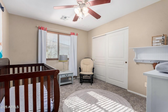 carpeted bedroom featuring a crib, a closet, and ceiling fan