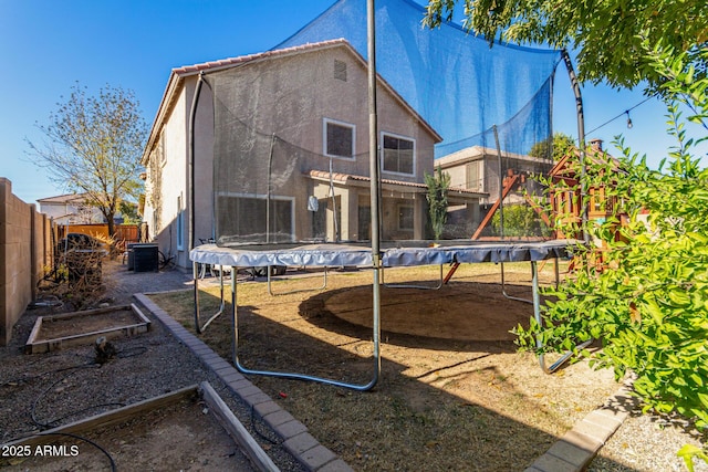 rear view of house featuring cooling unit and a trampoline