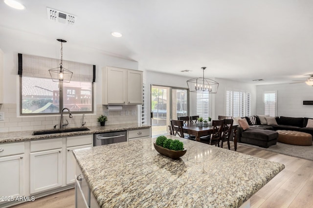 kitchen with dishwasher, a kitchen island, white cabinetry, and sink