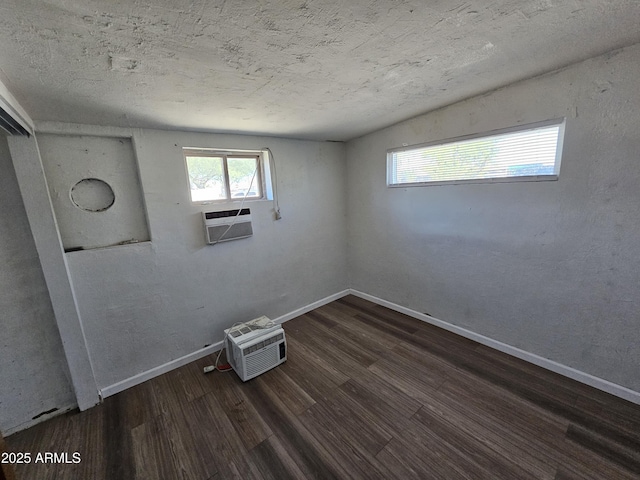 spare room with a wall unit AC, baseboards, cooling unit, and wood finished floors