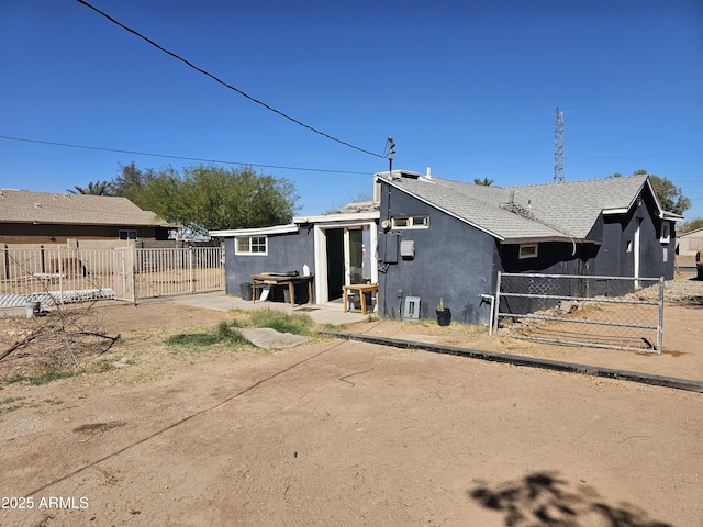 back of property with roof with shingles, fence, and stucco siding