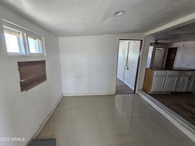 interior space featuring baseboards, a textured ceiling, and tile patterned floors