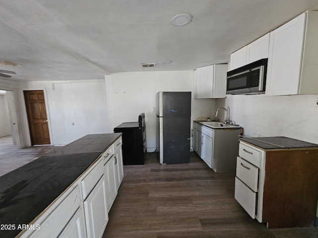 kitchen featuring visible vents, appliances with stainless steel finishes, dark wood-style flooring, white cabinetry, and a sink