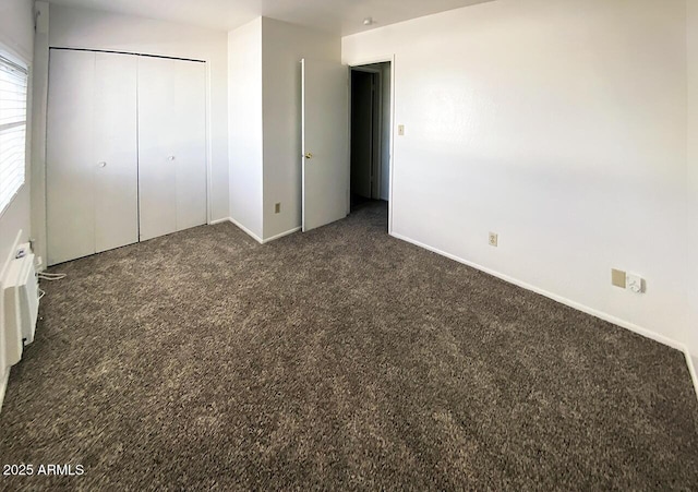 unfurnished bedroom with a closet and dark colored carpet