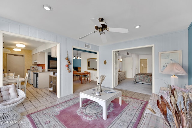 tiled living room featuring ceiling fan with notable chandelier