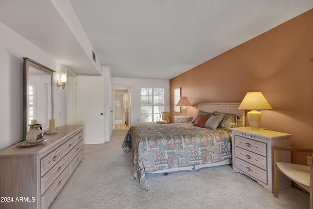 bedroom with ensuite bath and light colored carpet