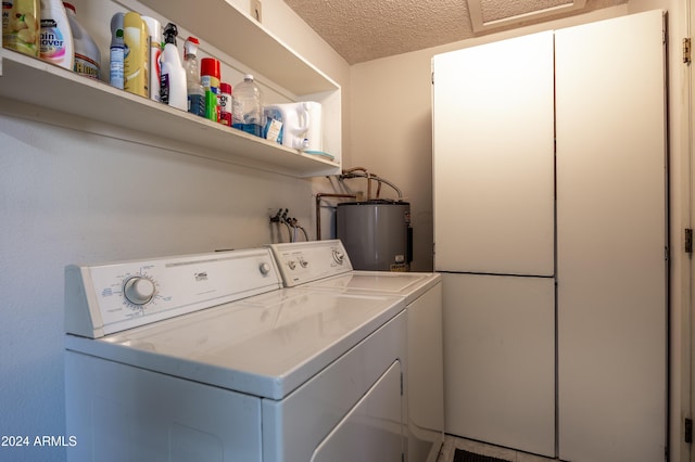 clothes washing area with a textured ceiling, washer and clothes dryer, and water heater