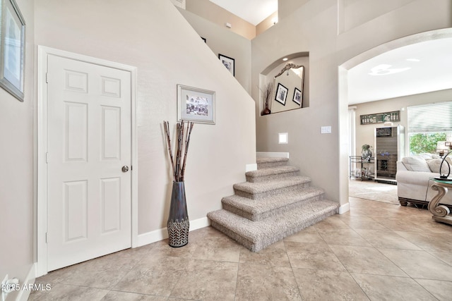 stairway with a towering ceiling and tile patterned flooring