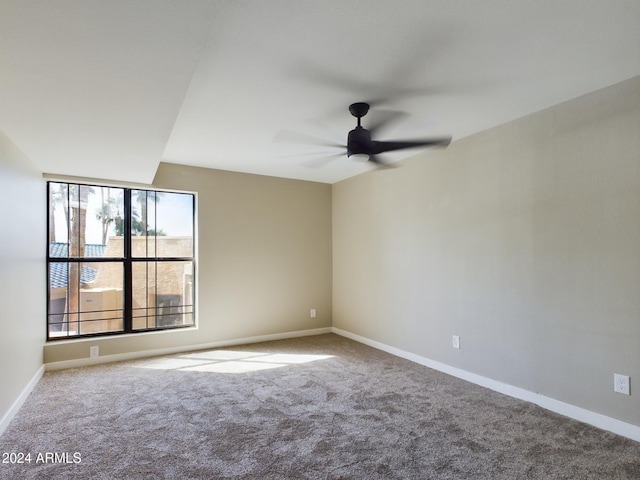 carpeted spare room featuring ceiling fan and baseboards