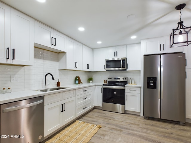 kitchen featuring appliances with stainless steel finishes, a sink, light countertops, light wood-style floors, and white cabinets