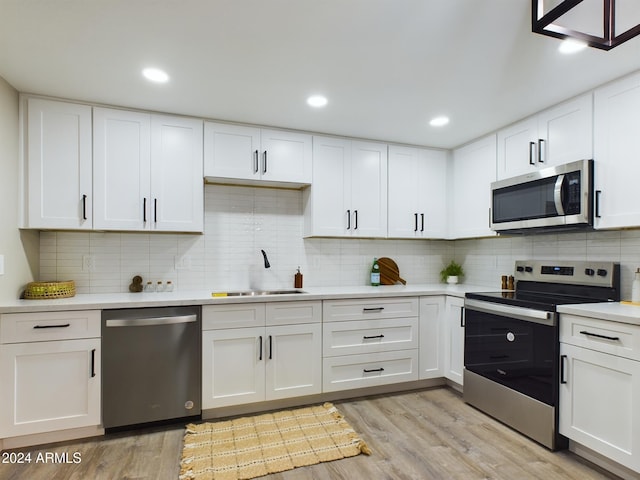 kitchen featuring stainless steel appliances, a sink, light countertops, light wood-style flooring, and recessed lighting