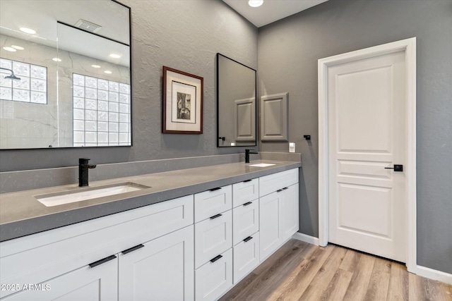 bathroom with hardwood / wood-style floors, vanity, and walk in shower