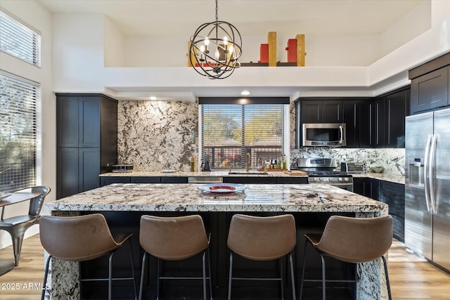 kitchen with decorative backsplash, appliances with stainless steel finishes, a kitchen island, and hanging light fixtures