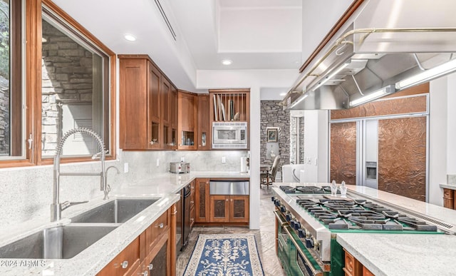 kitchen with appliances with stainless steel finishes, brown cabinetry, a sink, and tasteful backsplash