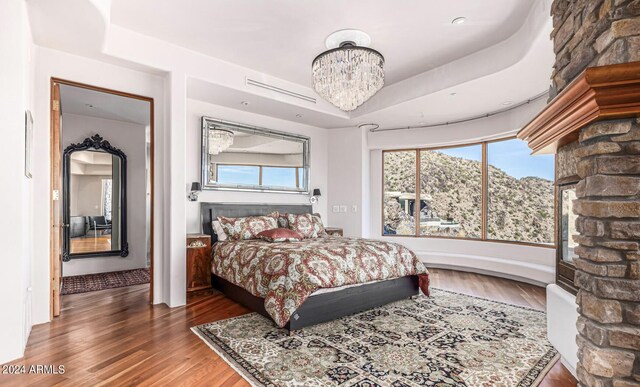 bedroom featuring hardwood / wood-style floors, a raised ceiling, and a chandelier