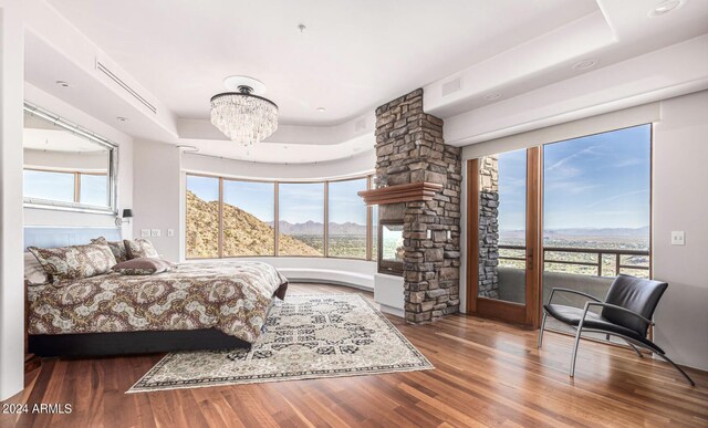 bedroom with a notable chandelier, a tray ceiling, hardwood / wood-style floors, and multiple windows