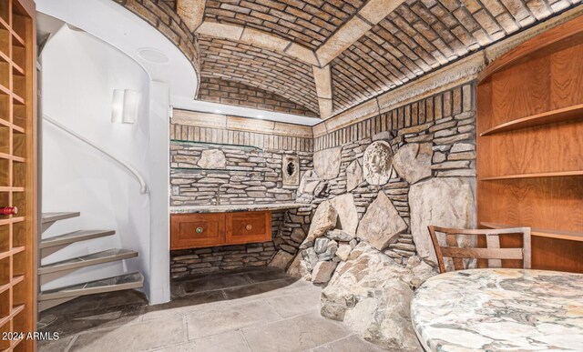 bathroom with tile patterned floors, vanity, vaulted ceiling, and brick ceiling