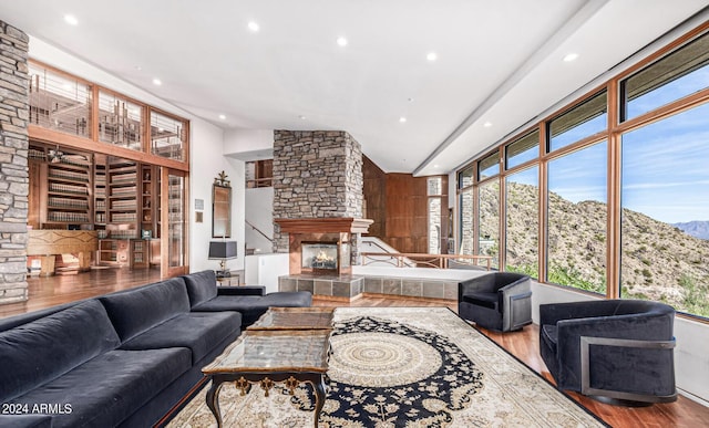 living room featuring high vaulted ceiling, a fireplace, and wood-type flooring