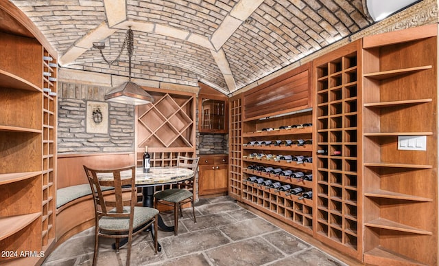 wine room featuring brick ceiling, lofted ceiling, and stone tile floors