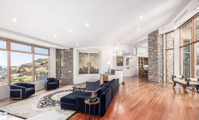 living room featuring a notable chandelier, vaulted ceiling, and light hardwood / wood-style floors