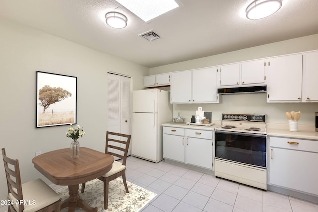 kitchen with white appliances, a skylight, a textured ceiling, light tile patterned floors, and white cabinets