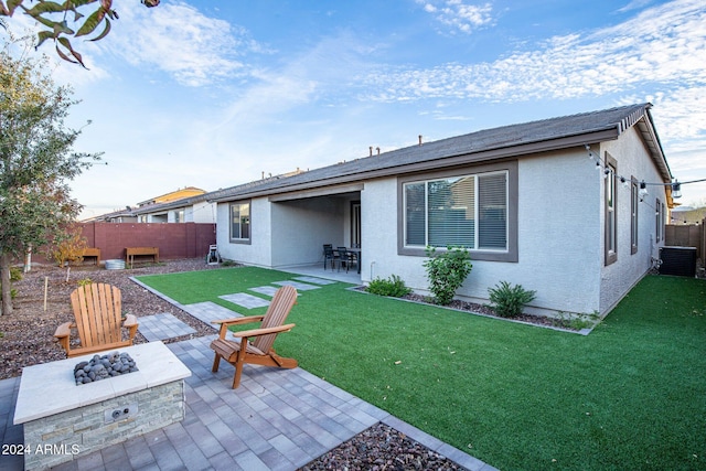 back of property featuring a patio area, a yard, cooling unit, and a fire pit