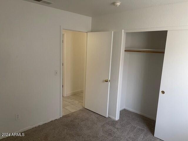 unfurnished bedroom featuring light carpet and a closet