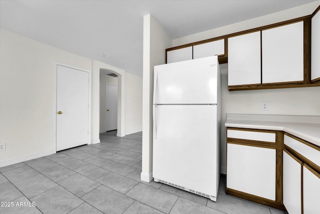 kitchen with white cabinets, white refrigerator, and light tile patterned floors