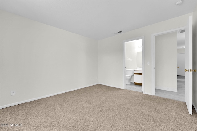 unfurnished bedroom featuring ensuite bathroom and light carpet