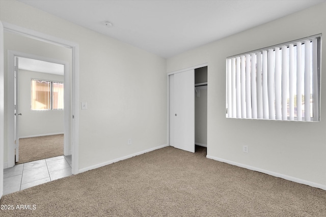 unfurnished bedroom with light carpet and a closet