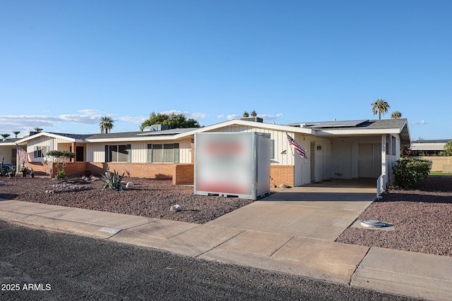 ranch-style home featuring a carport and solar panels