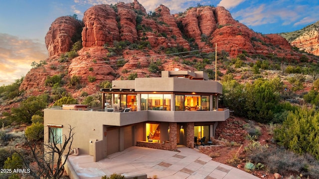 back house at dusk with a patio area and a mountain view