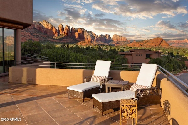 patio terrace at dusk with a balcony and a mountain view