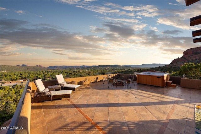 patio terrace at dusk featuring a mountain view and a hot tub