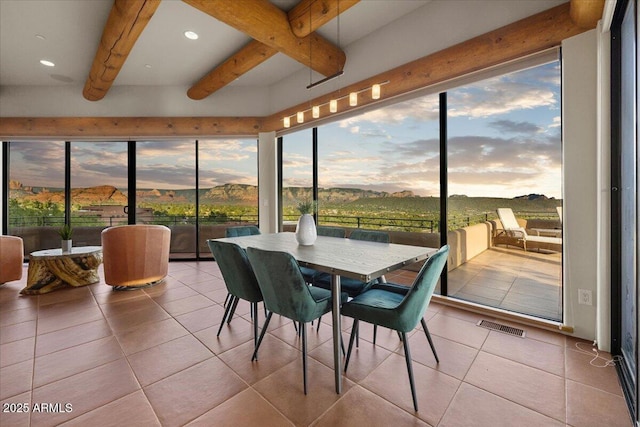 sunroom with a mountain view, beam ceiling, and a healthy amount of sunlight