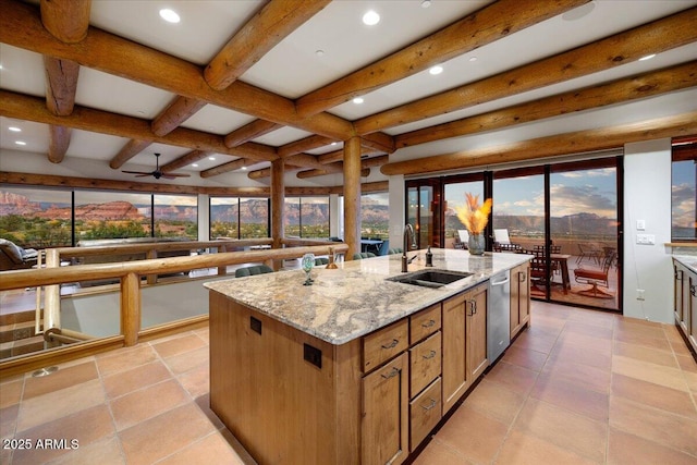 kitchen with a kitchen island with sink, light stone countertops, beam ceiling, sink, and stainless steel dishwasher