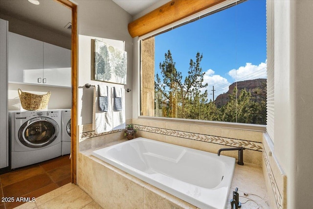 bathroom featuring washer and dryer, tile patterned flooring, and tiled bath