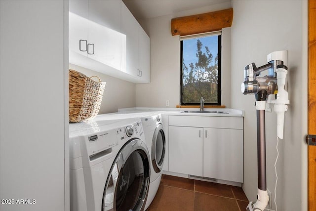 clothes washing area with cabinets, dark tile patterned flooring, washer and clothes dryer, and sink