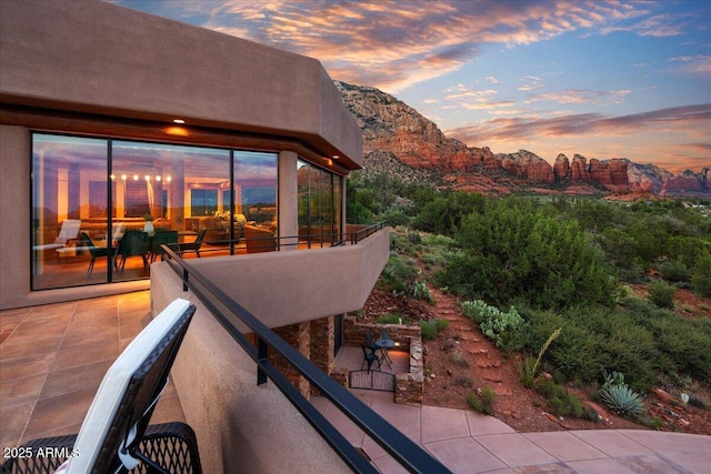 patio terrace at dusk featuring a balcony and a mountain view