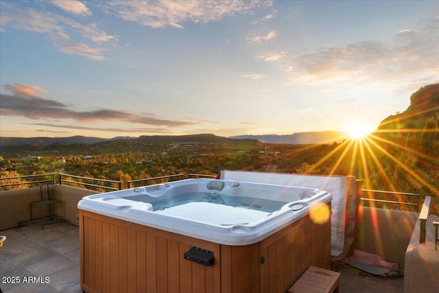 patio terrace at dusk with a hot tub and a mountain view