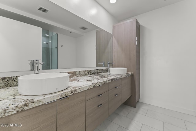 full bath with double vanity, visible vents, a shower stall, and a sink