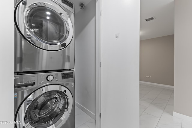 washroom with baseboards, visible vents, stacked washing maching and dryer, laundry area, and marble finish floor