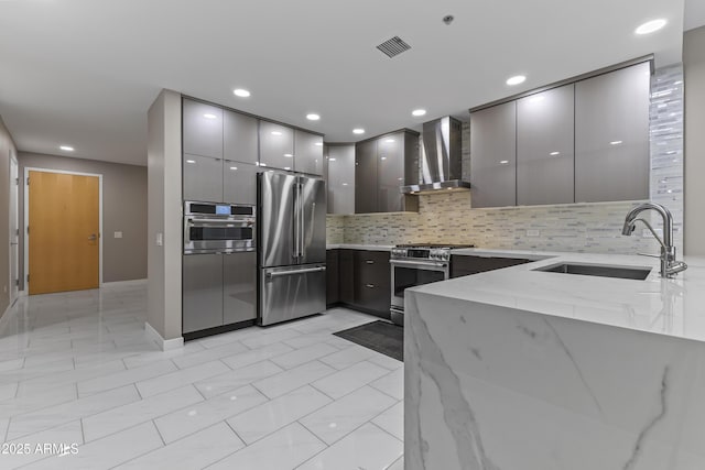 kitchen with a sink, gray cabinetry, wall chimney range hood, stainless steel appliances, and modern cabinets