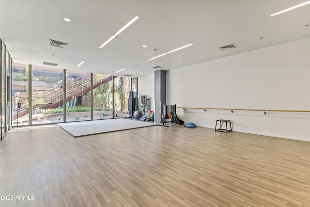 interior space with a wall of windows, light wood-style floors, and visible vents