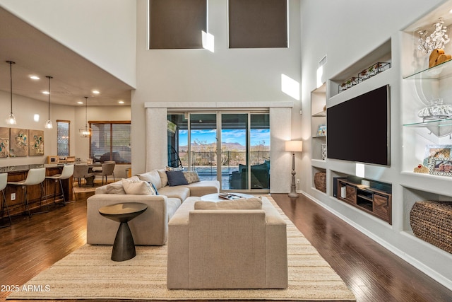 living room featuring built in features, a towering ceiling, and dark hardwood / wood-style floors