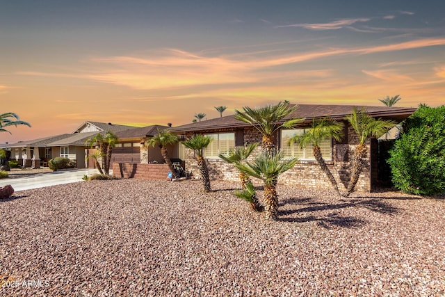 single story home with a garage, driveway, and brick siding