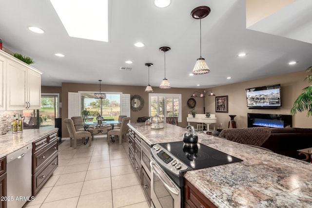 kitchen featuring stainless steel appliances, recessed lighting, visible vents, open floor plan, and light stone countertops