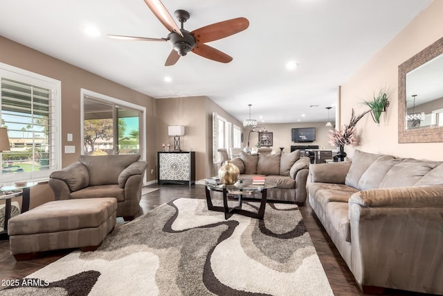 living room featuring dark wood-type flooring, recessed lighting, and ceiling fan with notable chandelier