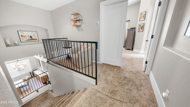 stairs with carpet floors, baseboards, and a chandelier