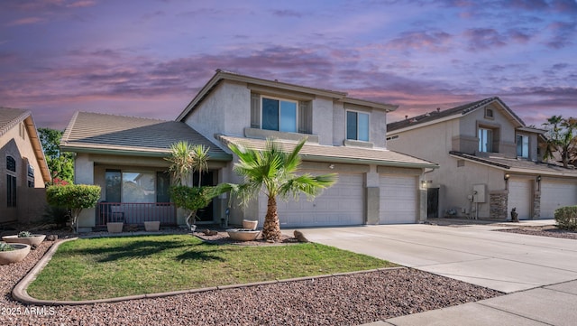 traditional-style house with a garage, a tile roof, driveway, and stucco siding